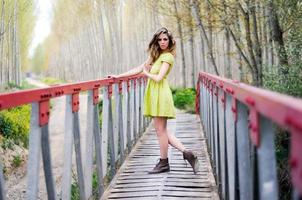 belle fille blonde, vêtue d'une robe beige, debout dans un pont rural photo