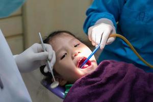 jeune dentiste et assistant dentaire faisant une procédure pour traiter les caries dentaires pour une fille en clinique