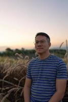 portrait d'homme debout dans un champ d'herbe au coucher du soleil photo