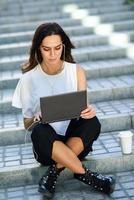 jeune femme travaillant avec son ordinateur portable assis sur le sol. photo