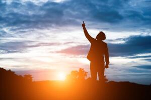 homme aux bras levés contre le beau coucher de soleil. photo