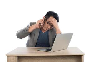 homme d'affaires stressé parlant au téléphone travail avec ordinateur portable assis à table isolé sur fond blanc. photo