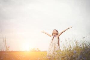 petite fille asiatique mignonne debout parmi le jour de soleil de champ de fleurs pourpres. la liberté de profiter de la nature. photo