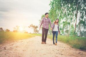 jeune couple hipster marchant sur une route rurale profitant de la nature, couple amoureux, voyages de vacances, passer du temps ensemble. photo