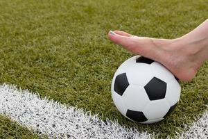 pied de fille sur le ballon de football sur le champ vert photo