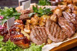 plusieurs types de viande rôtie aux épices et herbes sur un plateau en bois photo