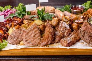 plusieurs types de viande rôtie aux épices et herbes sur un plateau en bois photo