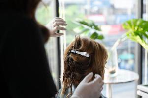 femme cliente ayant un processus de traitement d'un cheveu avec un coiffeur dans un salon de beauté photo