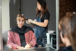 femme cliente ayant un processus de traitement d'un cheveu avec un coiffeur dans un salon de beauté photo