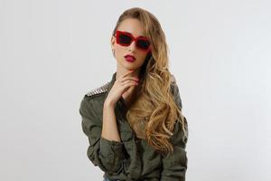 visage de femme gros plan dans des lunettes de soleil rouges isolés sur fond blanc. fille en chemise, maquillage des lèvres rouges. concept de beauté de mode. belle peau de visage et accessoires à la mode. cheveux longs style glamour photo