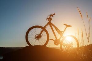 VTT silhouette sur le rocher au coucher du soleil du ciel photo