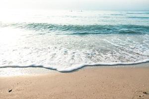 gros plan vague sable plage écume de mer. gros plan de la vague de mer avec de la mousse sur le sable de la plage. fond de vacances d'été photo