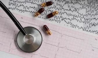 stéthoscope médical avec pilules et cardiogramme sur fond clair. vue de dessus photo