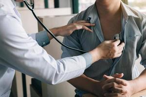 un médecin asiatique utilise un stéthoscope pour écouter le rythme cardiaque du patient âgé. photo