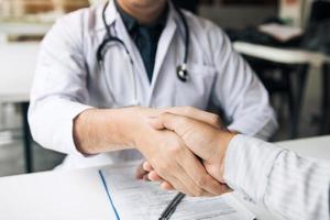 médecin serrant la main d'un patient plus âgé dans la salle de la clinique. photo