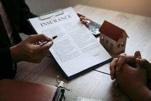 les agents utilisent des stylos pointant vers les contrats d'assurance et sont expliqués aux clients au bureau. photo