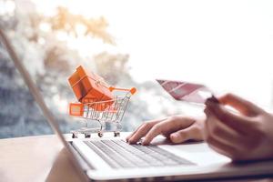 concept de magasinage en ligne avec une main de femme utilisant un ordinateur portable et à la recherche d'une carte de crédit pour le produit de commande d'achat. photo