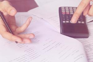 les gens d'affaires comptant sur la calculatrice assis à la table. gros plan des mains et de la papeterie, flou artistique photo