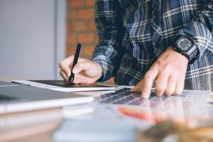 designers créatifs indépendants travaillant sur un bureau à l'aide d'une tablette graphique numérique et dessinant avec un stylo dans un bureau à domicile moderne. photo