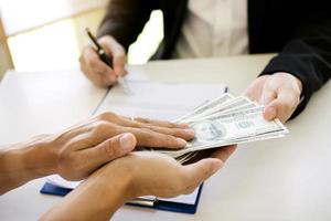 de l'argent entre les mains d'hommes d'affaires qui se soumettent à des entrepreneurs pour forcer la signature de documents contractuels sur le concept de corruption. photo