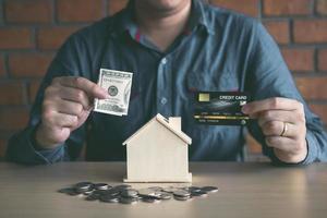 les hommes utilisent des billets de banque dans la tirelire de la maison avec l'idée de collecter de l'argent pour acheter une nouvelle maison. photo