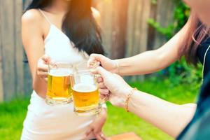 gros plan adolescent tinter le verre avec de la bière dans le jardin. photo