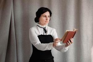 femme de style vintage habillée tenant un livre dans ses mains sur un fond de toile de lin photo