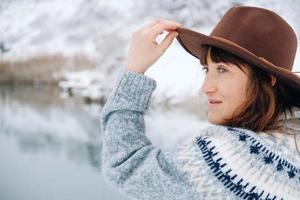 portrait d'une femme dans un chapeau et un pull marron en feutre sur fond de paysage d'hiver photo