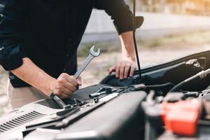 le mécanicien automobile tient une clé prête à vérifier le moteur et l'entretien. photo