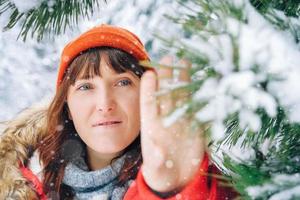 belle femme dans une veste chaude rouge et un chapeau dans une forêt d'hiver enneigée photo