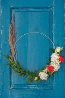 couronne décorée de fleurs, de feuilles et d'herbe sèche sur un fond de porte bleue en bois. copie, espace vide pour le texte photo