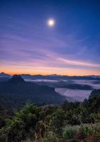 point de vue brume montagne colorée avec la lune à l'aube photo