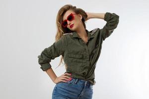 femme élégante à lunettes rouges regardant la caméra au studio isolé sur fond blanc. espace de copie. style branché de beau modèle de luxe avec maquillage des lèvres rouges. longs cheveux blonds ondulés brillants photo