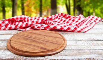 planche à pizza vide sur une table en bois vide avec nappe, serviette - vue de dessus photo