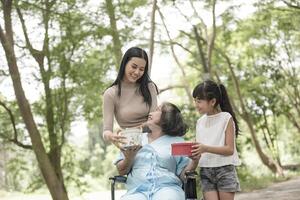 petite-fille a une surprise pour grand-mère assise sur un fauteuil roulant. photo