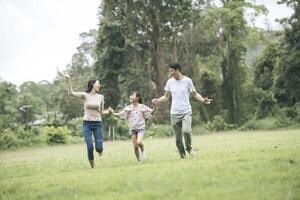 une famille heureuse s'amuse mère, père et fille courent dans le parc. photo