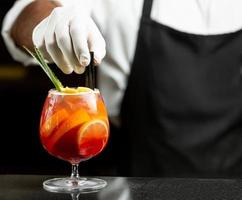le serveur met des pailles en plastique dans un cocktail de sangria en verre