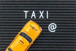concevez simplement le modèle de taxi de voiture de jouet jaune avec le mot de lettres de taxi d'inscription sur le fond noir. symbole de l'automobile et du transport. concept d'idée de service urbain de livraison de trafic urbain. espace de copie. photo
