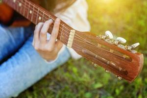 mains de femme jouant de la guitare acoustique photo