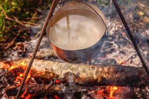 marmite en fonte cuisine sur feu ouvert dans un camping en forêt en été ensoleillé. camping tourisme relax voyage mode de vie actif aventure voyage concept de pique-nique. photo