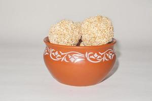 Bonbon indien pour le festival traditionnel makar sankranti rajgira laddu à base de graines d'amarante dans un bol sur fond blanc. photo
