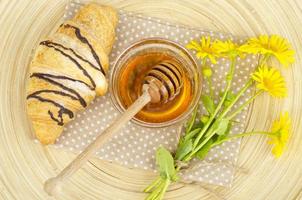 croissant frais, miel, fleurs jaunes. photo