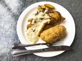 quartiers de pommes de terre avec sauce aux champignons, escalope sur assiette. photo