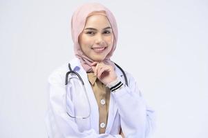 femme médecin musulmane avec hijab sur fond blanc studio.