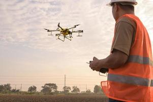 ingénieur masculin contrôlant la pulvérisation d'engrais et de pesticides par drone sur les terres agricoles, les innovations de haute technologie et l'agriculture intelligente photo