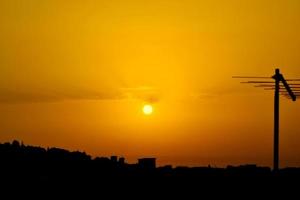 coucher de soleil jaune orange avec la silhouette d'une antenne sur le côté droit photo