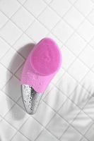 brosse sonique faciale rose pour massage sur carrelage blanc avec gouttes d'eau photo