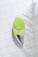 brosse faciale sonique verte pour massage, sur carrelage avec gouttes d'eau photo
