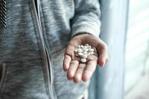 La main de l'homme avec un médicament renversé du contenant de la pilule photo