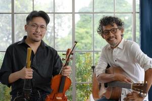 portrait de deux musiciens asiatiques souriants tenant une guitare et un violon photo